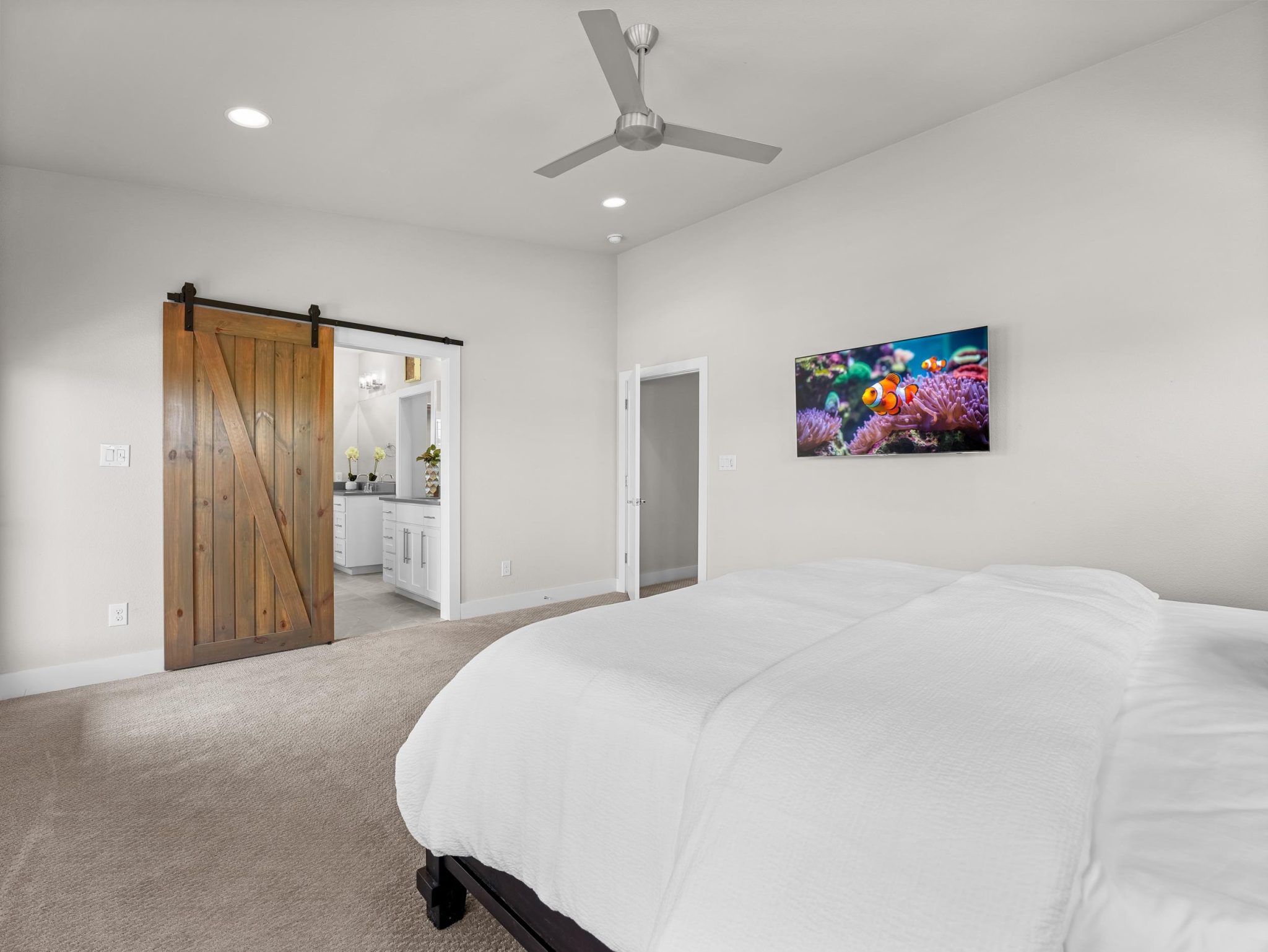 A spacious bedroom connects to an en suite bathroom through a sliding barn door.
