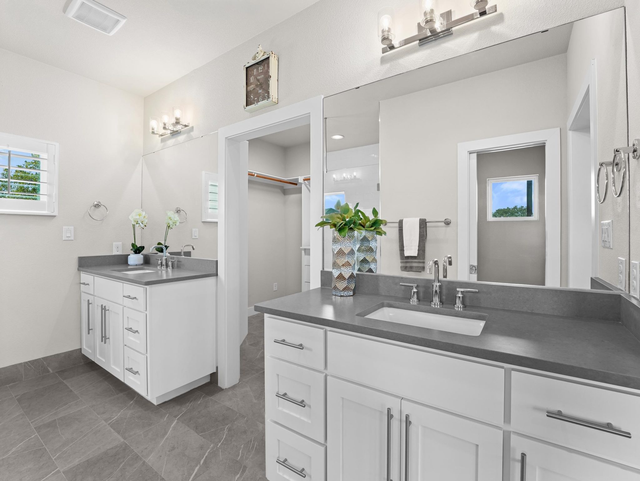 Dual vanities with solid stone counters flank a central walk-in closet entryway.