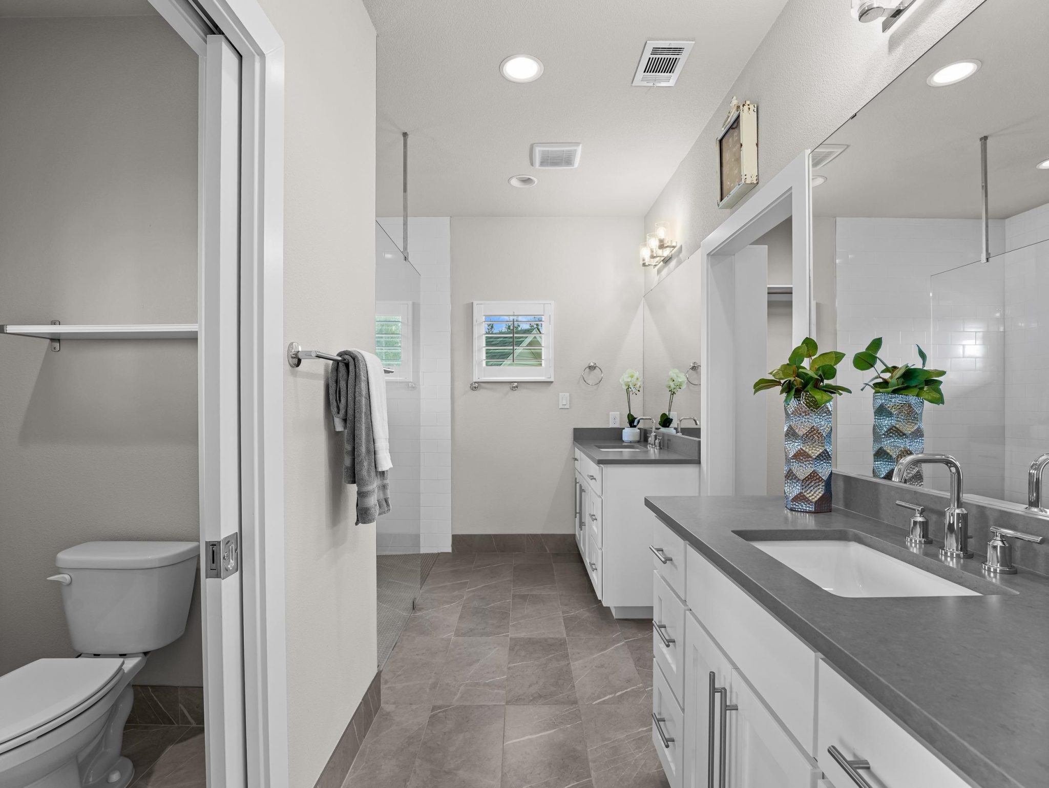Clean lines and durable stone counters define this modern bathroom with neutral tile flooring.
