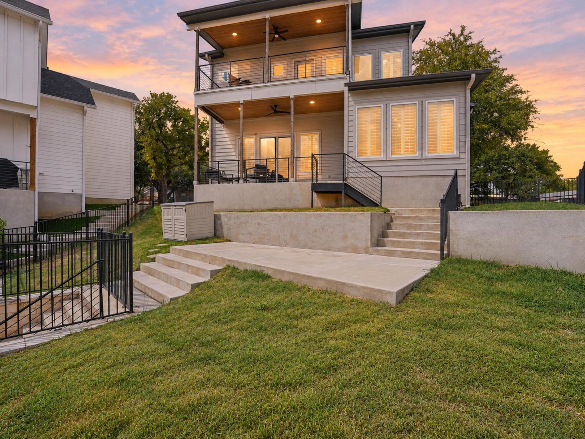 Multi-level concrete terraces and manicured lawns frame the modern back exterior of this home